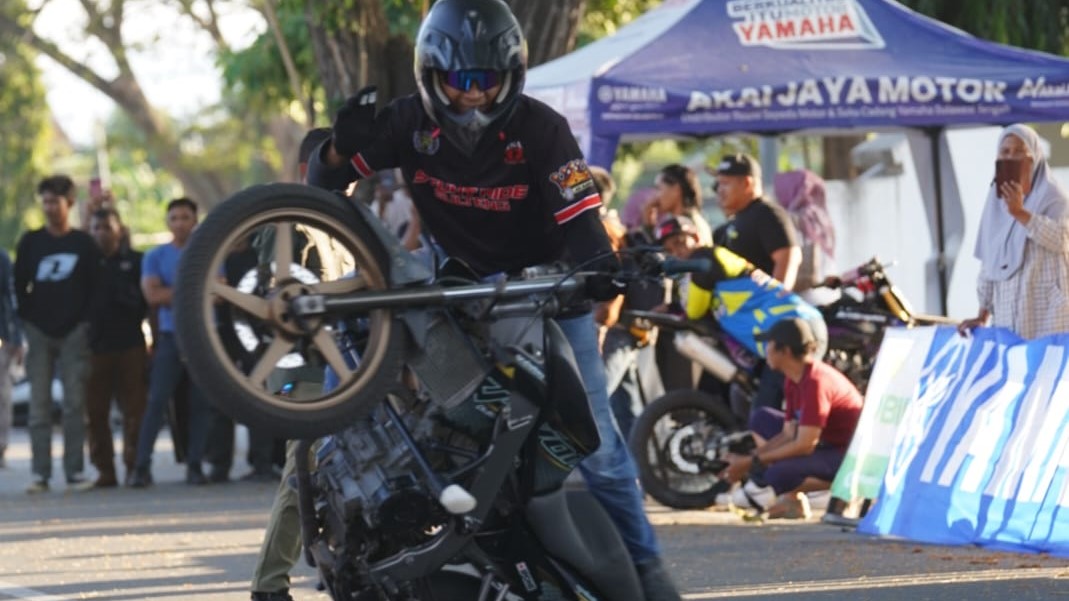 Stunt rider Kota Palu melakukan aksi ekstrem di atas motor dalam kompetisi freestyle.