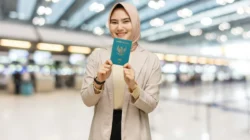 Perempuan berjilbab menunjukkan paspor Republik Indonesia di bandara.