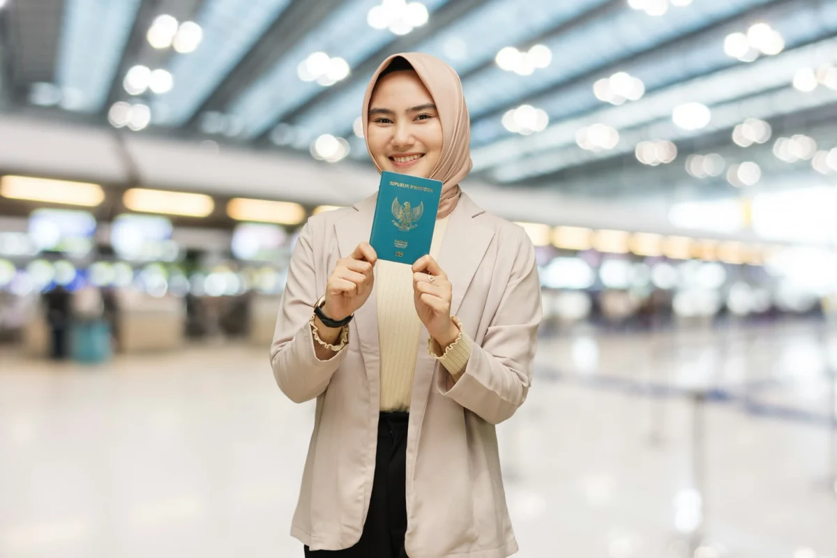 Perempuan berjilbab menunjukkan paspor Republik Indonesia di bandara.